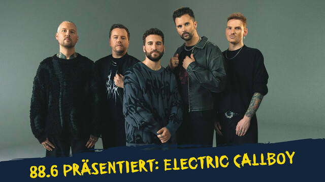 Die Bandmitglieder von Electric Callboy stehen vor einem grauen Hintergrund