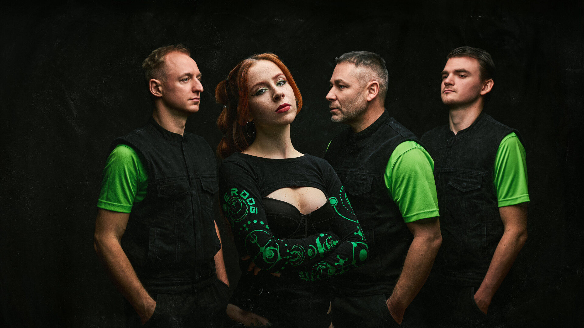 Die Band steht in schwarzer Kleidung mit neongrünen Akkzenten in einem Dunklen Rraum