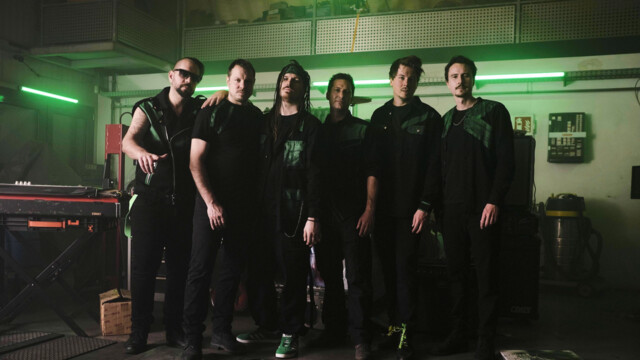 Band steht in schwarzer kleidung in einem grün Beleuchtetem Proberaum