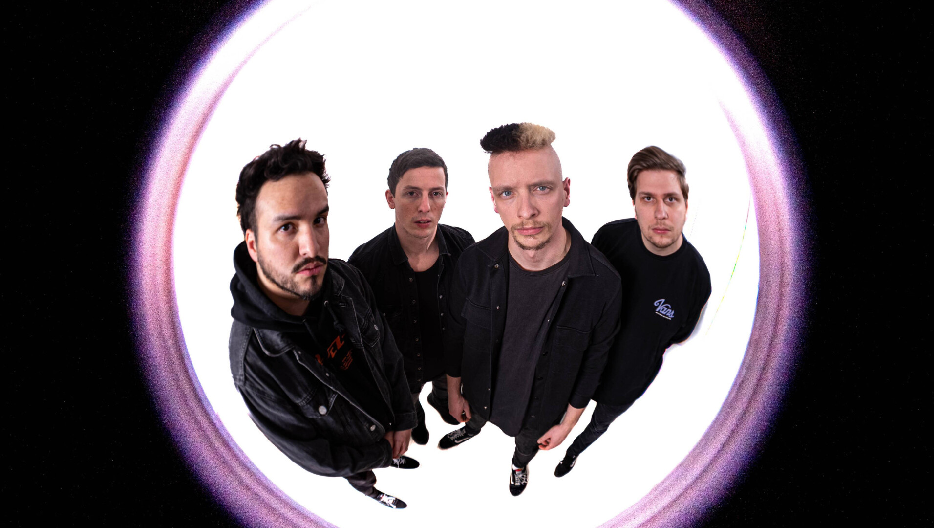 Ein Fischaugenfoto mit pinkem Rand in dem die Band Here For A Reason in schwarzer Kleidung steht