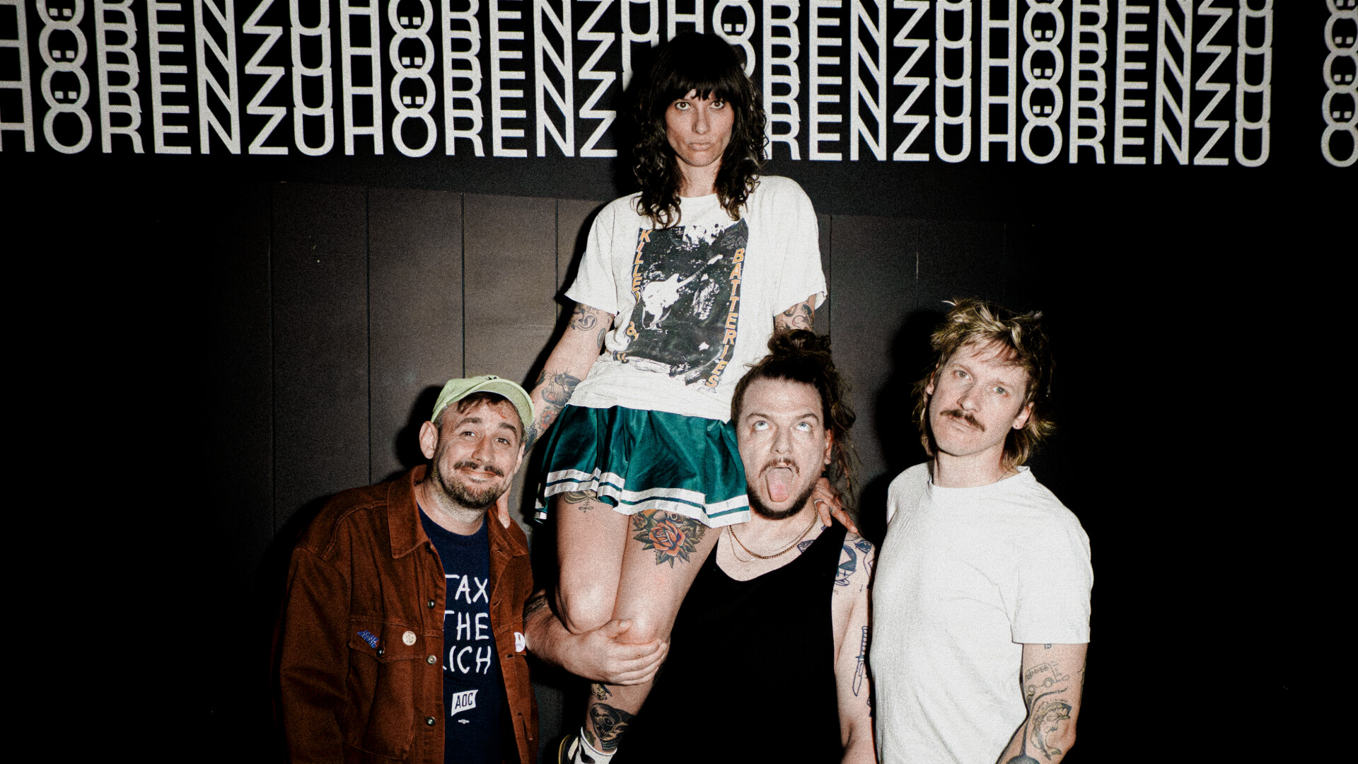 Die Band Baits trägt ihre Sängerin vor schwarzem Hintergrund auf den Schultern