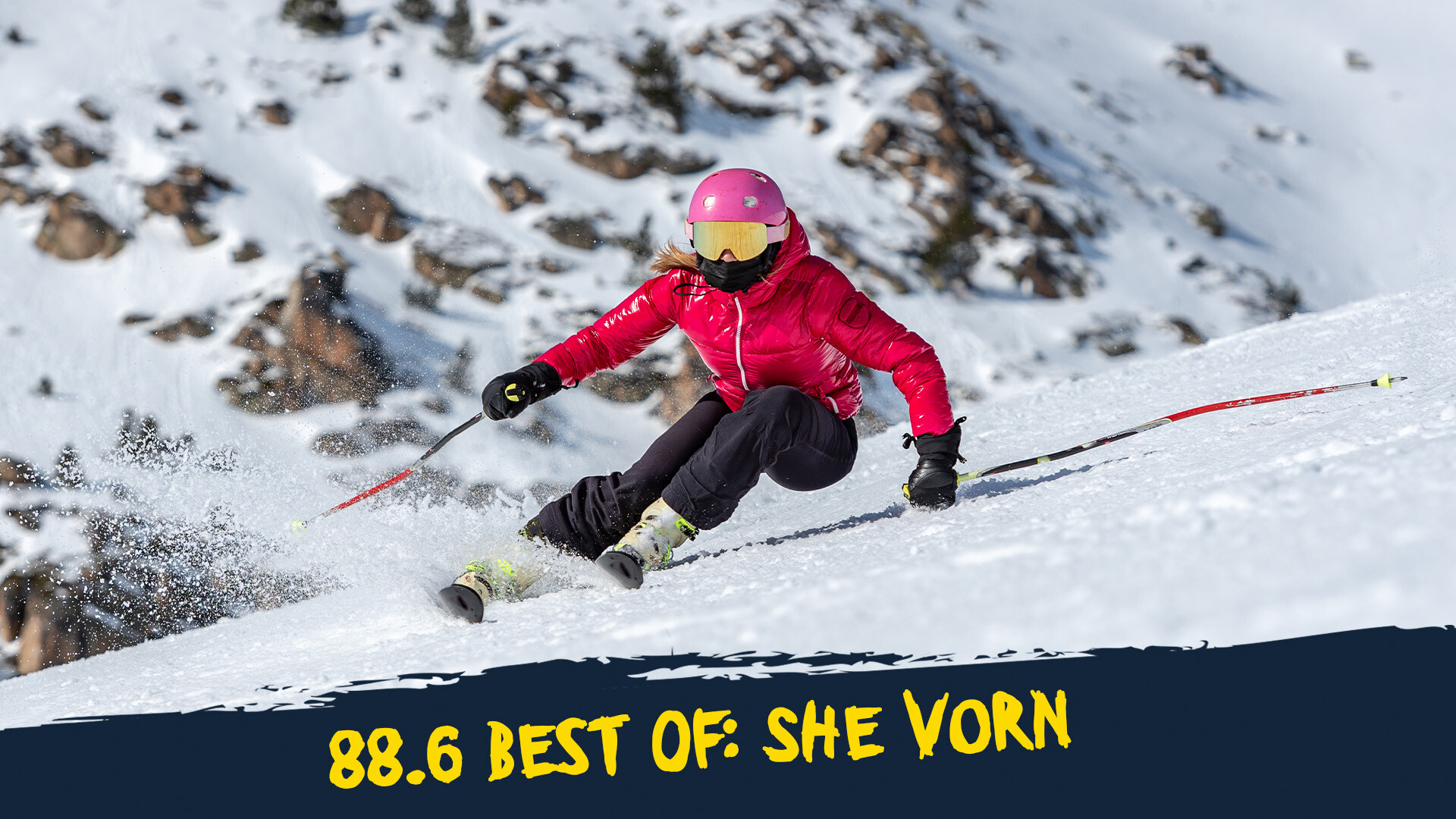 Skifahrerin mit pinkem Helm, roter Jacke und schwarzer Hose auf der Piste