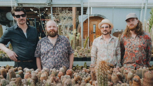 Die Band steht in sommerlichen Hemden in einem Kaktusshop