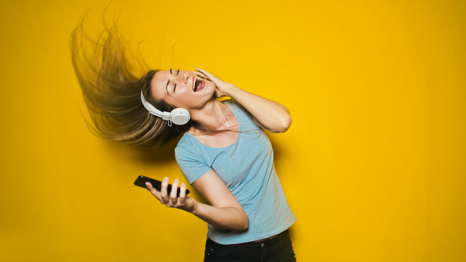 Photo by bruce mars from Pexels Eine Frau, die auf Kopfhörern Musik hört und dabei mitsingt.