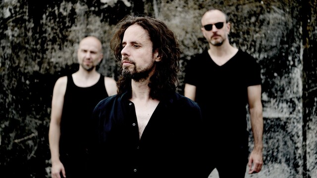 Bandfoto von Forced To Mode, alle drei Mitglieder tragen schwarz